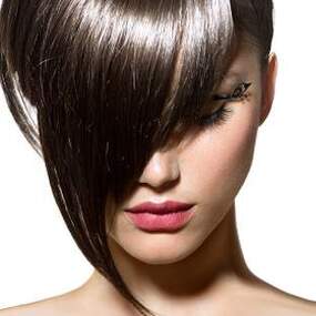 Frau mit glattem, braunem Bob-Haarschnitt und kreativem Augen-Make-up vor weißem Hintergrund.