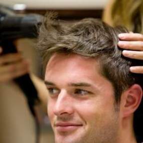 Mann bekommt im Friseursalon die Haare geföhnt, professionelle Haarpflege und Styling.